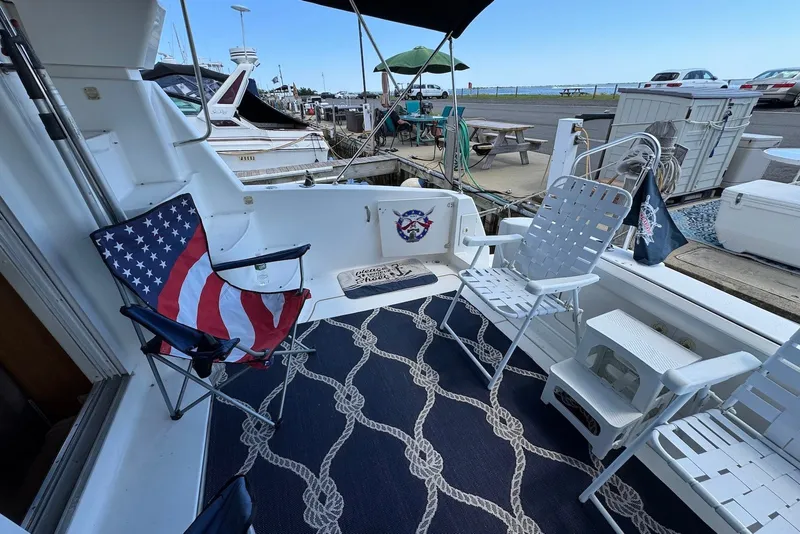 Slide: The Image of 1999 Silverton 351 Sedan boat deck with chairs, nautical rug, and American flag theme. - 6