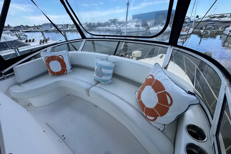 Slide: The Image of 1999 Silverton 351 Sedan boat interior with cushioned seating and nautical-themed pillows. - 7