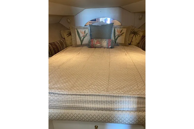 Slide: The Image of 1999 Silverton 351 Sedan cabin with a neatly made bed and decorative pillows. - 8