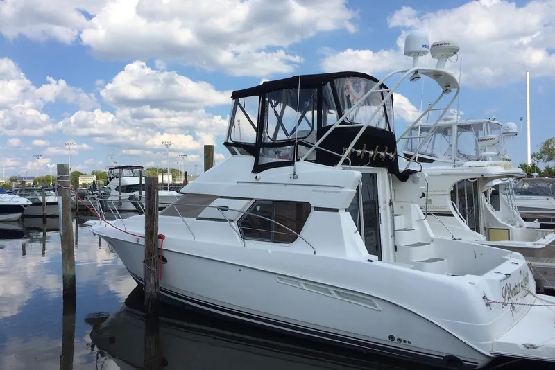 The Image of 1999 Silverton 351 Sedan yacht docked at marina under blue sky. - 0