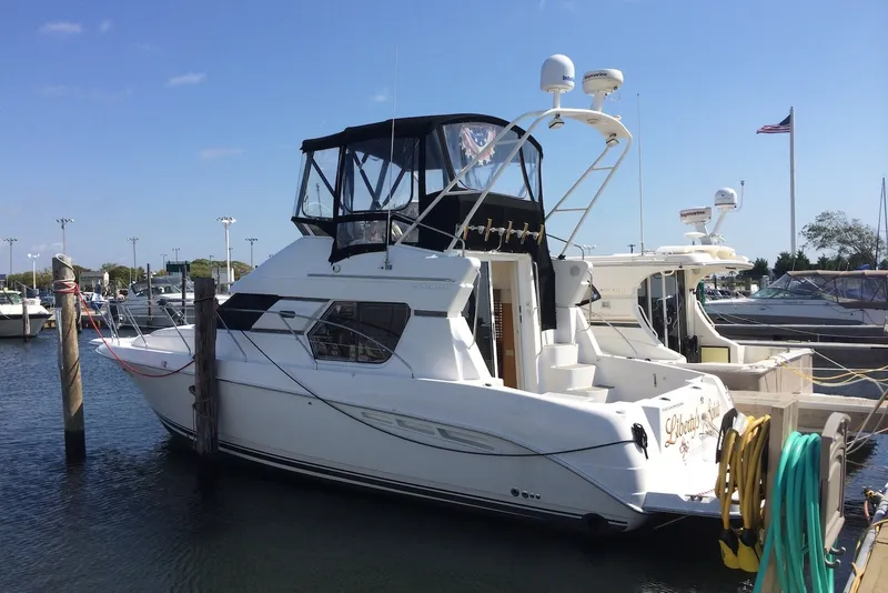 Slide: The Image of 1999 Silverton 351 Sedan yacht docked at a marina under clear blue skies. - 4