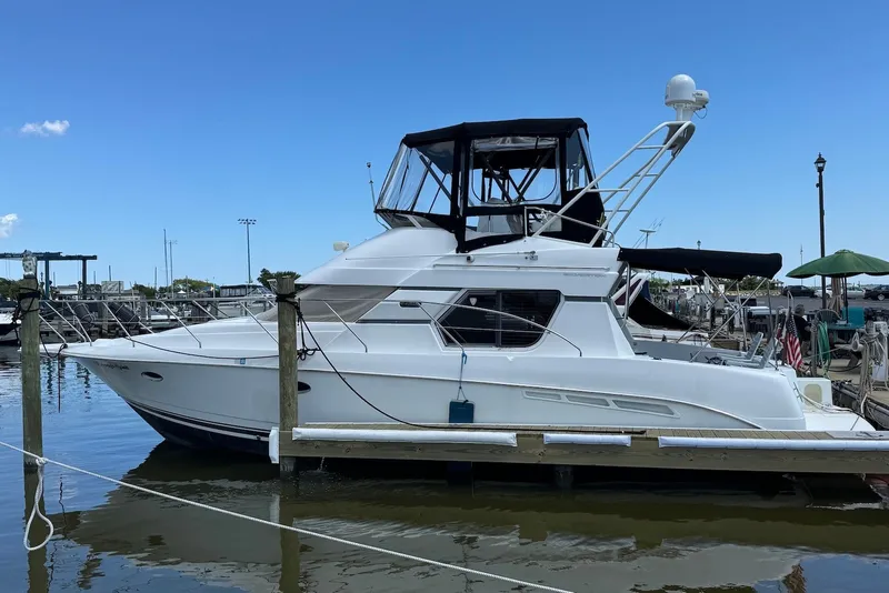 The Image of 1999 Silverton 351 Sedan yacht docked at marina under clear blue sky. - 0