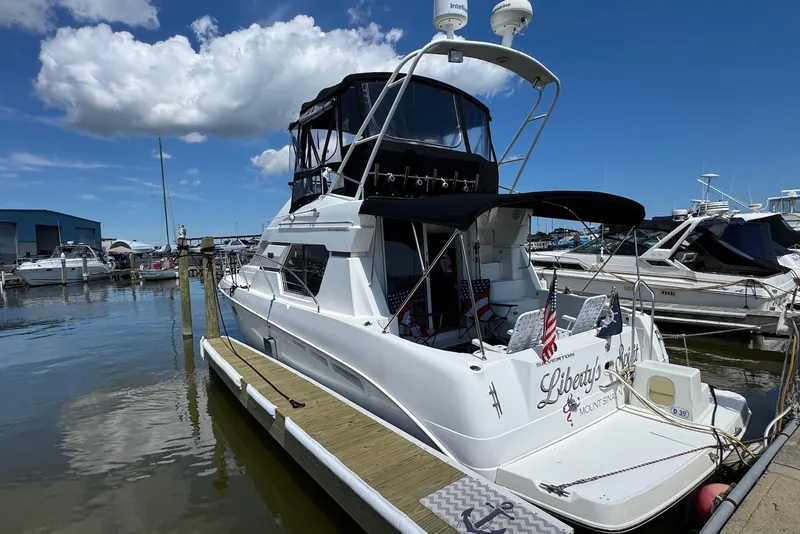 Slide: The Image of 1999 Silverton 351 Sedan yacht docked at marina under blue sky. - 1