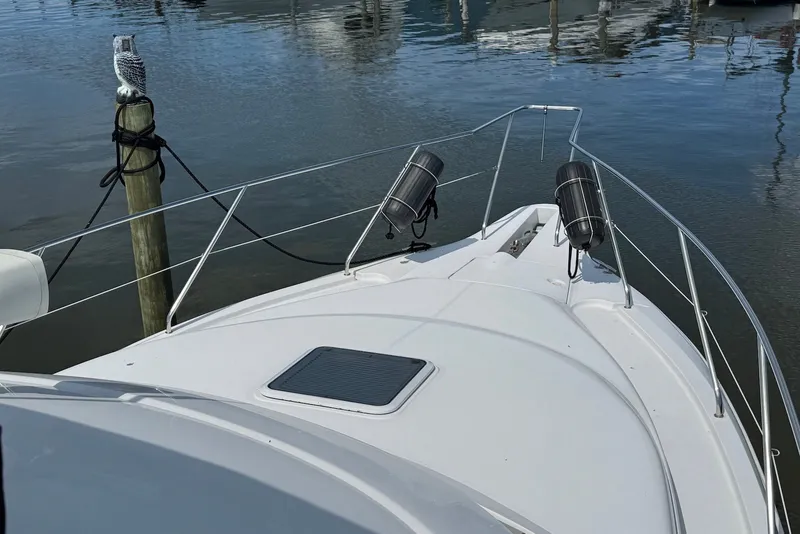 Slide: The Image of 1999 Silverton 351 Sedan boat bow with docked owl statue, calm water background. - 3