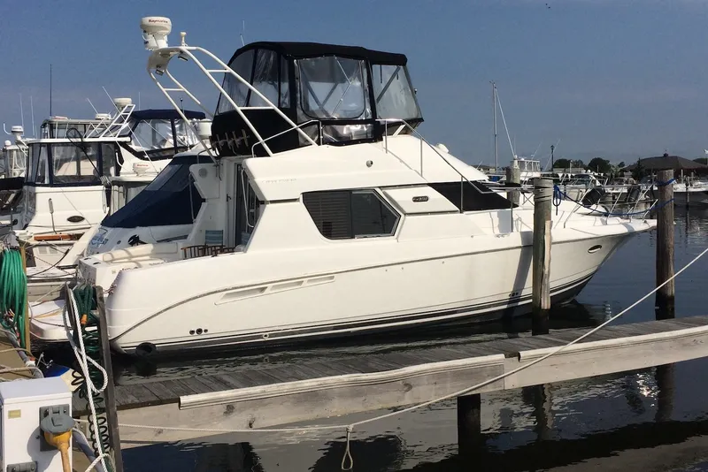 Slide: The Image of 1999 Silverton 351 Sedan yacht docked at marina, featuring sleek white design and spacious cabin. - 1