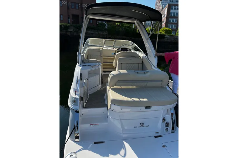 Slide: The Image of 2019 Regal 28 Express boat with beige seating and black canopy docked by buildings. - 4
