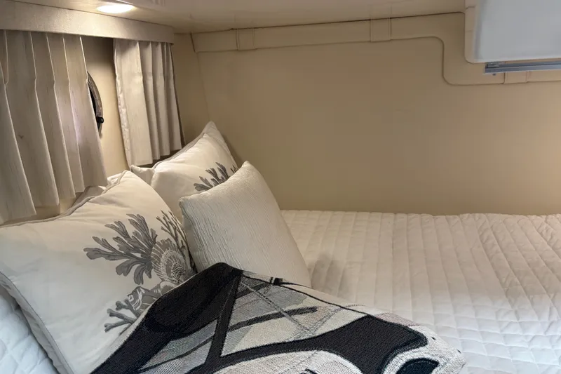 Slide: The Image of Cozy cabin interior of 2019 Regal 28 Express with decorative pillows and blanket. - 37