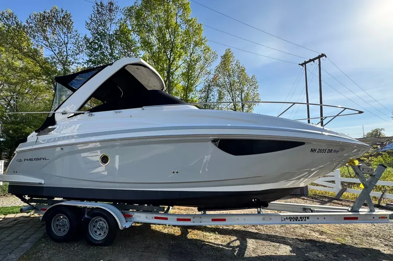Slide: The Image of 2019 Regal 28 Express boat on trailer, surrounded by trees and clear sky. - 3