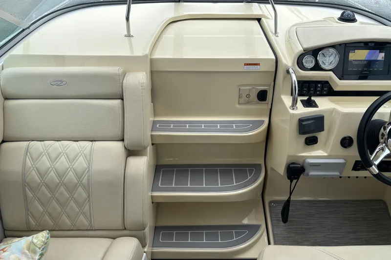 Slide: The Image of Interior of a 2019 Regal 28 Express boat, featuring beige seating and modern dashboard controls. - 23