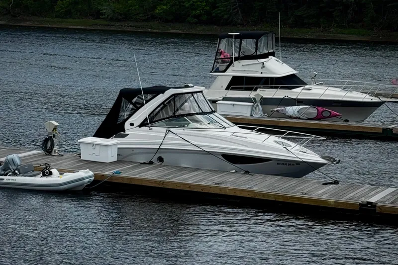 The Image of 2019 Regal 28 Express boat docked on a calm lake with nearby vessels. - 0