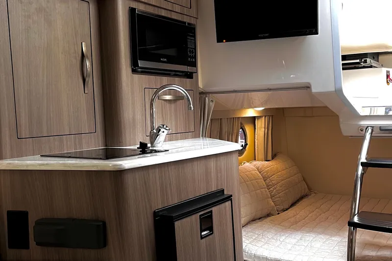 Slide: The Image of Interior of a 2019 Regal 28 Express boat featuring a kitchenette and cozy sleeping area. - 5