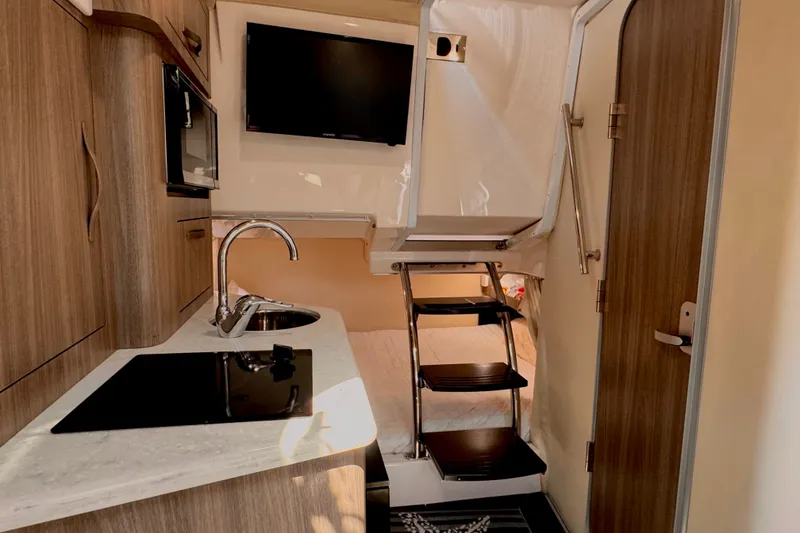 Slide: The Image of 2019 Regal 28 Express cabin interior with kitchenette, stairs, and modern amenities. - 10