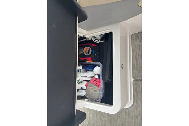 Slide: The Image of Storage compartment in a 2019 Regal 28 Express boat, filled with various items. - 15