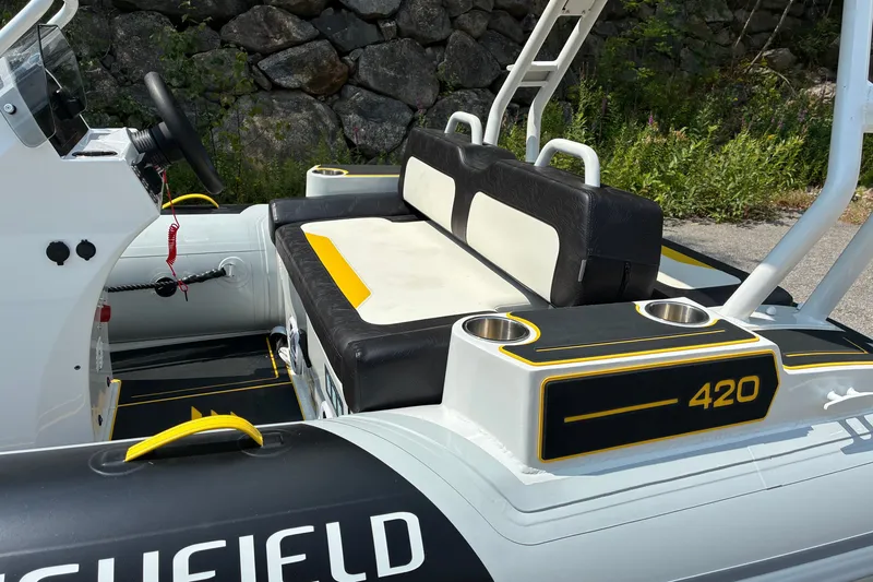 Slide: The Image of 2026 Highfield Velox 420 boat interior with black and white seating, cup holders, and control panel. - 10