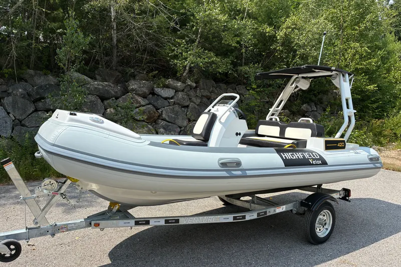 Slide: The Image of 2026 Highfield Velox 420 inflatable boat on trailer, parked outdoors near trees and rocks. - 1