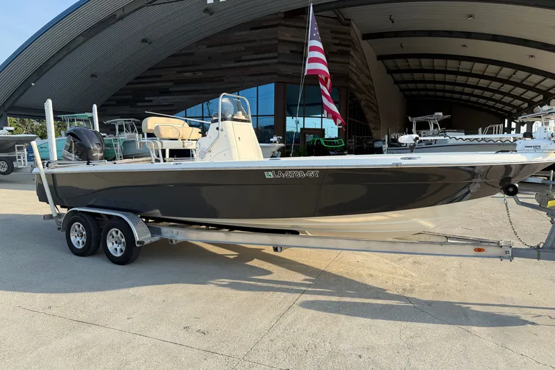 Slide: The Image of 2018 NauticStar 244 XTS boat on trailer, parked outside a modern building. - 2