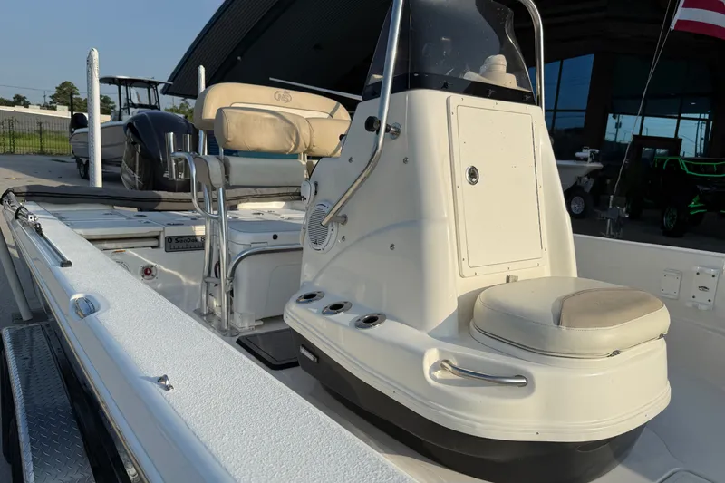 Slide: The Image of 2018 NauticStar 244 XTS boat interior with seating and console, docked outdoors. - 14