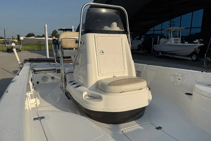 Slide: The Image of 2018 NauticStar 244 XTS boat interior with console and seating, docked outdoors. - 16