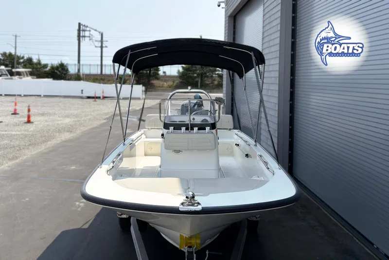 Slide: The Image of 2018 Boston Whaler 170 Montauk boat with canopy, parked near a building. - 2