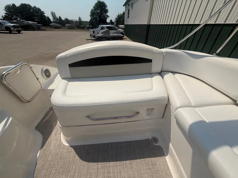 Slide: The Image of The image shows the white, cushioned seating area of a 2011 Chaparral 244 Sunesta boat parked on a lot. - 26