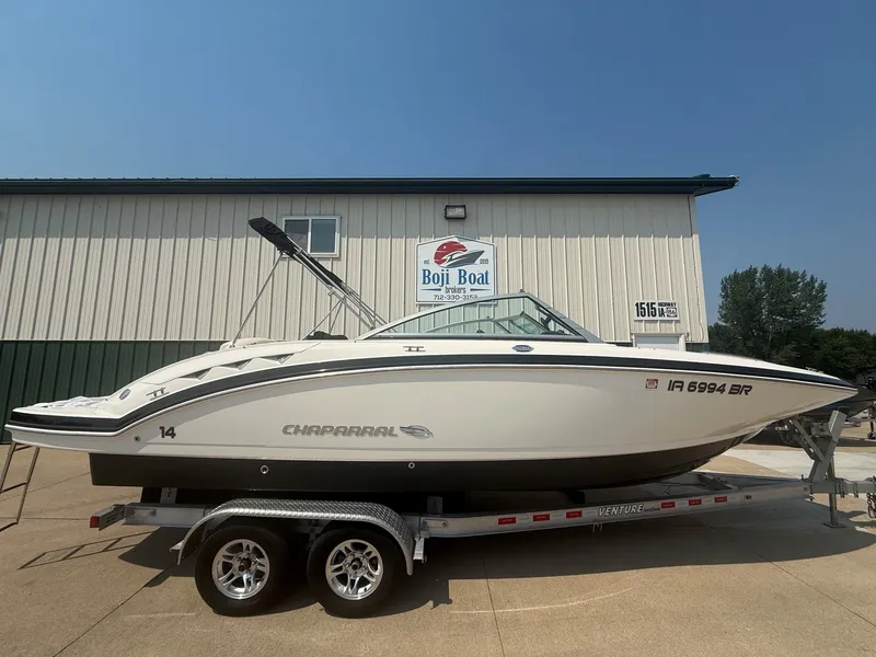 The Image of A white 2011 Chaparral 244 Sunesta boat on a trailer in front of a building. - 0