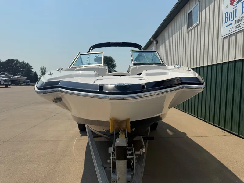 Slide: The Image of A white 2011 Chaparral 244 Sunesta boat on a trailer in front of a building. - 2