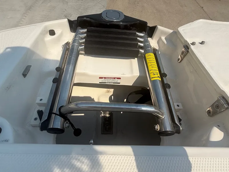 Slide: The Image of A swim ladder on a 2011 Chaparral 244 Sunesta boat, featuring stainless steel handles and safety stickers. - 14