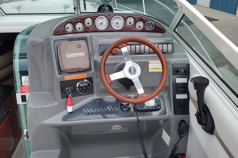 Slide: The Image of 2006 Doral Monticello 250 boat dashboard with Garmin GPS and wooden steering wheel. - 14