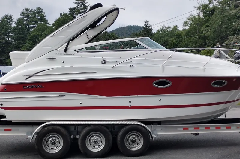 Slide: The Image of 2006 Doral Monticello 250 boat on trailer, white and red design, parked outdoors. - 5