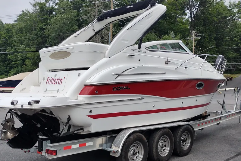 Slide: The Image of 2006 Doral Monticello 250 boat on trailer, white and red design, parked outdoors. - 6