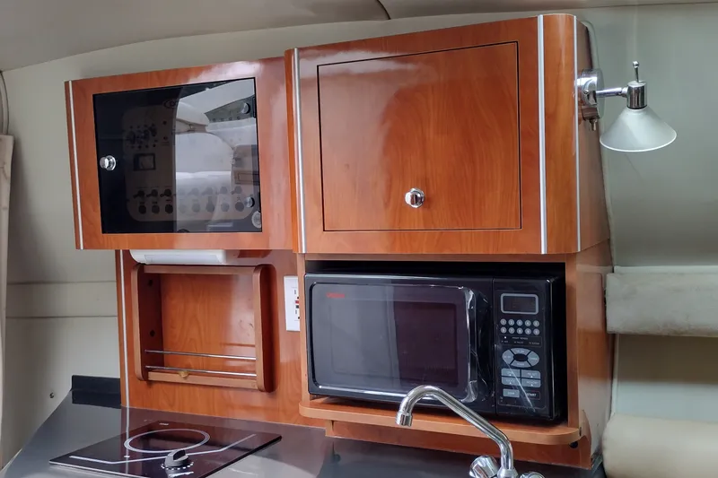 Slide: The Image of Interior of a 2006 Doral Monticello 250 boat kitchen with microwave and wooden cabinets. - 24