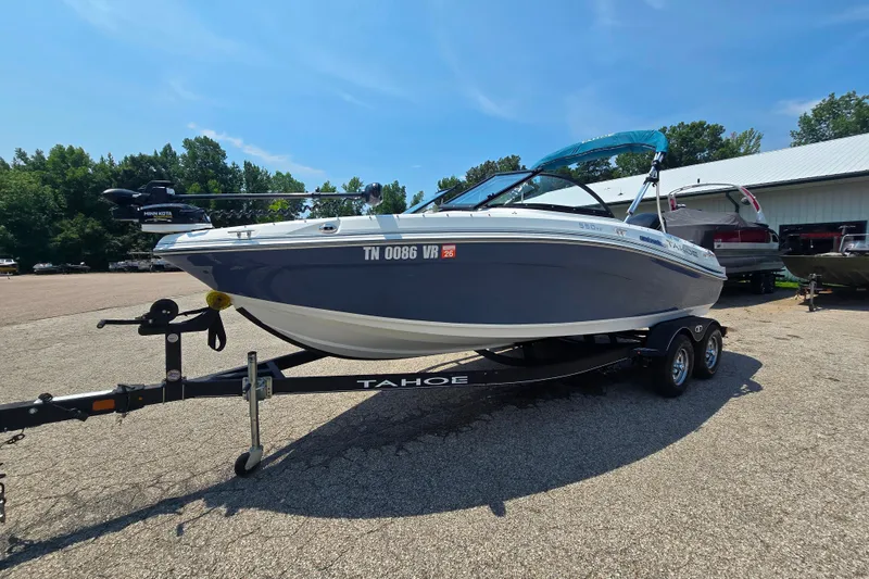 The Image of 2021 Tahoe 550 TF boat on trailer, parked outdoors under clear blue sky. - 0