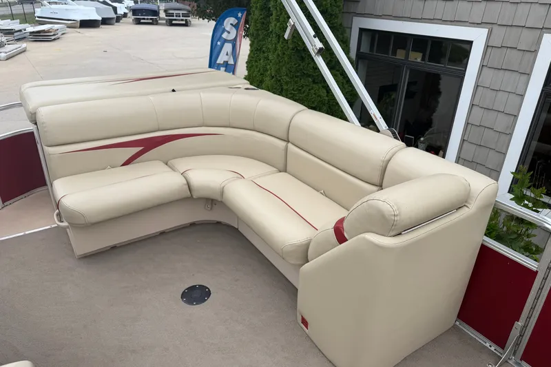 Slide: The Image of 2011 Harris Cruiser 220 boat with beige seating and red accents, docked near a building. - 6