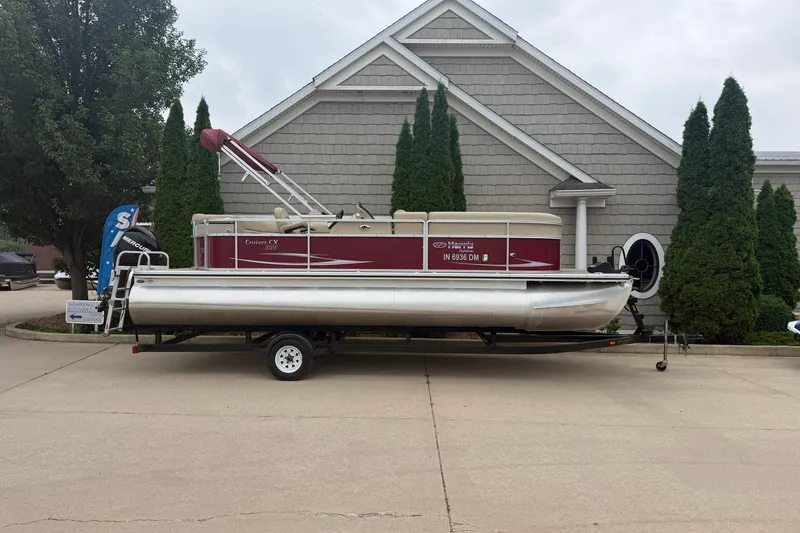 The Image of 2011 Harris Cruiser 220 pontoon boat on trailer, parked near a building. - 1