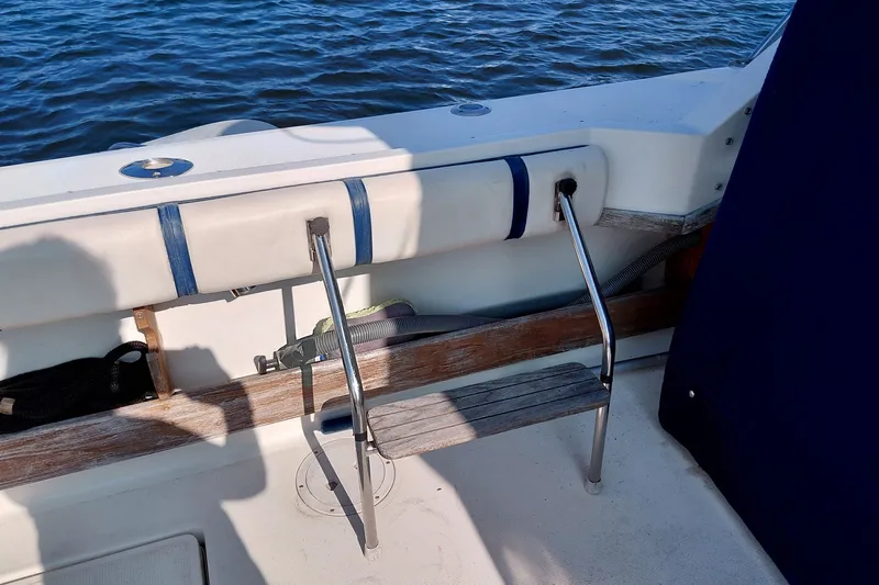 Slide: The Image of 1991 Tiara Yachts 3100 Open boat interior with ladder and railing by the water. - 13