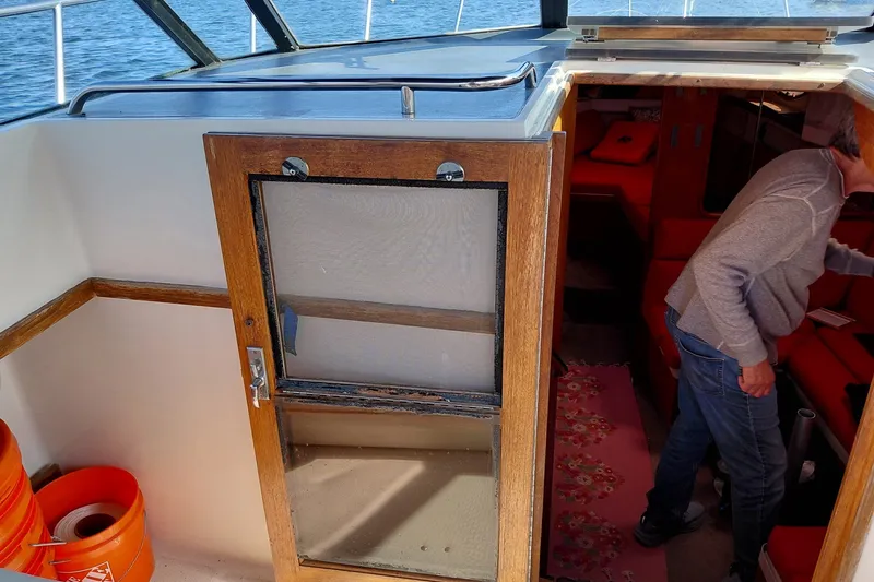 Slide: The Image of 1991 Tiara Yachts 3100 Open interior with wooden door and person entering cabin. - 16