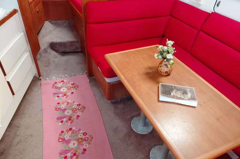 Slide: The Image of Interior of a 1991 Tiara Yachts 3100 Open with red seating, wooden table, and floral decor. - 24