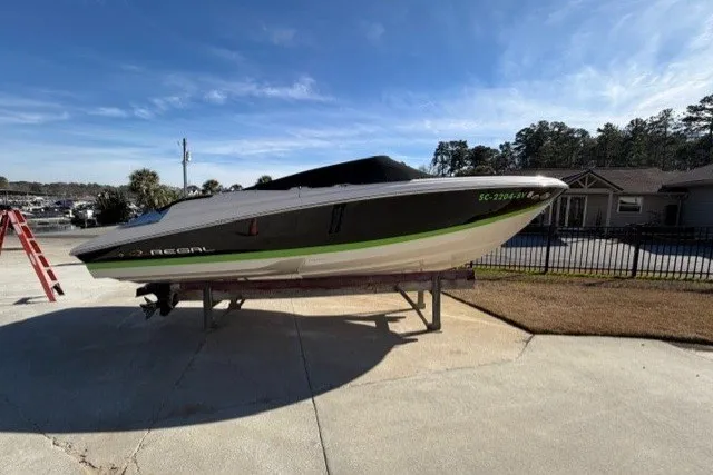 Slide: The Image of 2005 Regal 2200 Bowrider boat on trailer, parked outdoors under clear blue sky. - 16