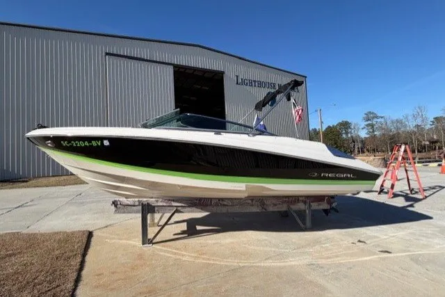Slide: The Image of 2005 Regal 2200 Bowrider boat on stand, outside a large warehouse. - 2