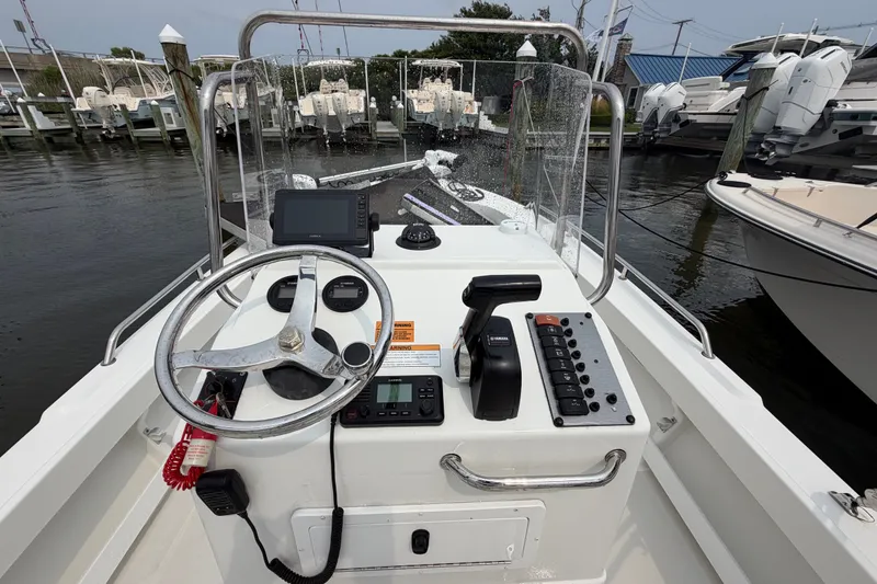 Slide: The Image of 2024 Parker 1801 Center Console boat dashboard with steering wheel and controls at marina. - 12
