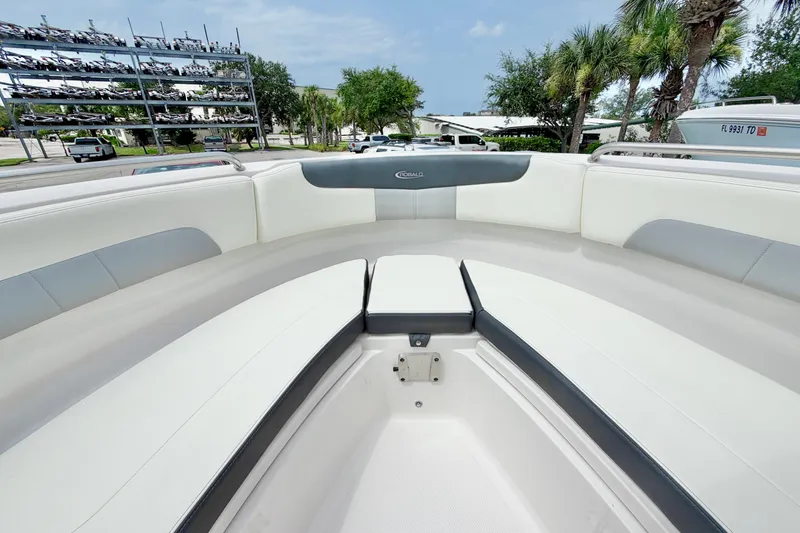 Slide: The Image of 2024 Robalo R222 Center Console boat interior with white seating and palm trees in background. - 29