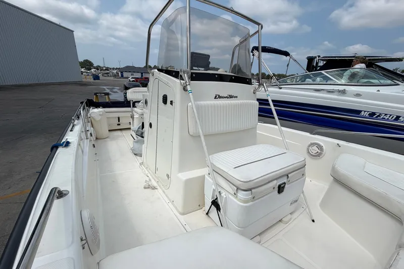 Slide: The Image of 2000 Boston Whaler 22 Dauntless boat interior with seating and storage, docked beside another vessel. - 11