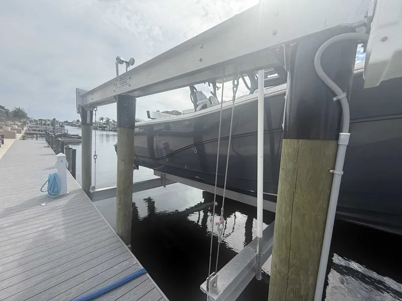 Slide: The Image of A 2025 Sea Fox 328 Commander is suspended on a boat lift next to a dock. - 7