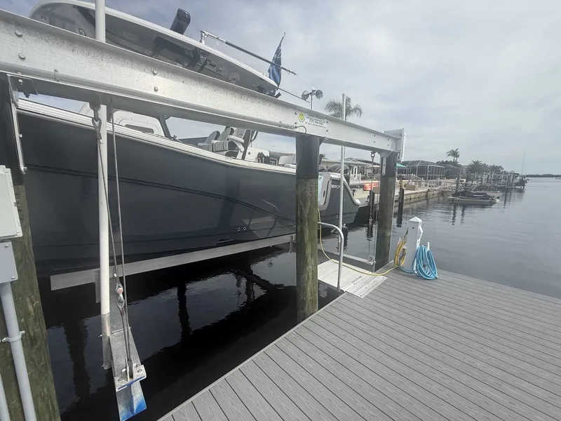 Slide: The Image of A 2025 Sea Fox 328 Commander is on a boat lift at a dock. The sky is cloudy. - 9