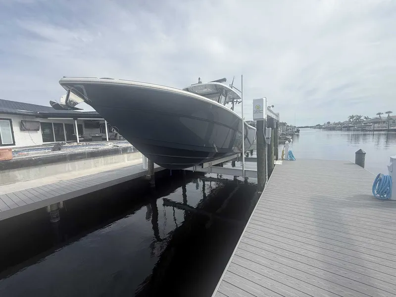 Slide: The Image of A 2025 Sea Fox 328 Commander is on a boat lift at a dock. It's a modern motorboat. - 13