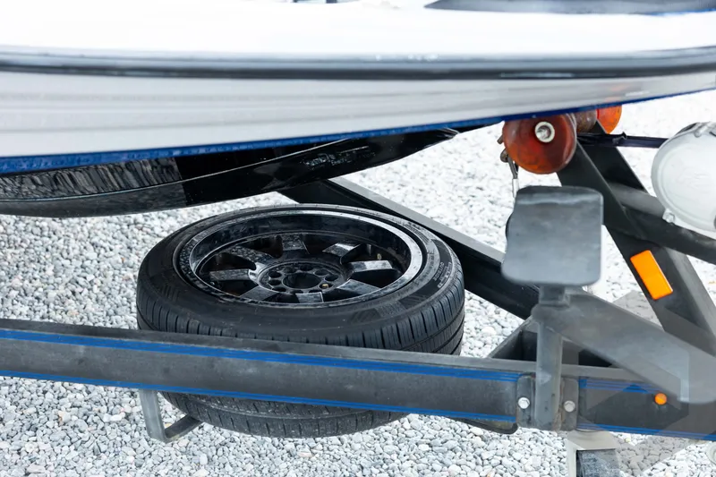 Slide: The Image of 2020 Skeeter FXR20 Limited boat trailer with spare tire on gravel surface. - 10
