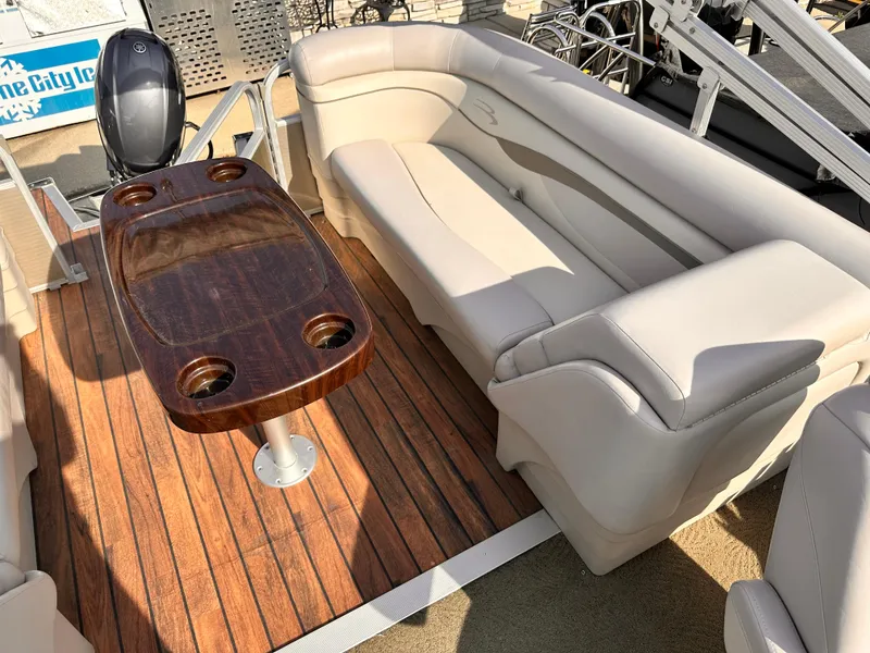 Slide: The Image of 2015 Bennington S24 boat interior with beige seating and wooden table. - 13