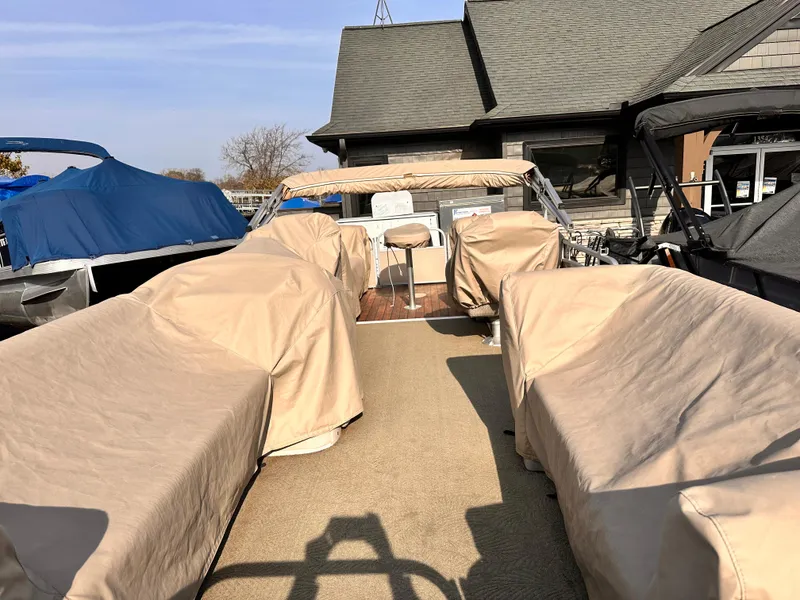 Slide: The Image of 2015 Bennington S24 pontoon boat with beige covers, docked near a house. - 20