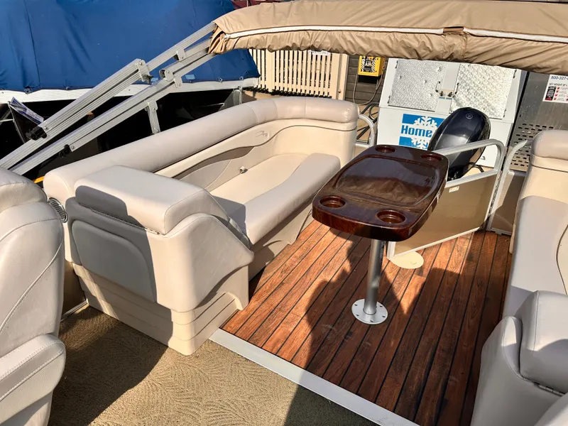Slide: The Image of 2015 Bennington S24 boat interior with beige seating and wooden table. - 14