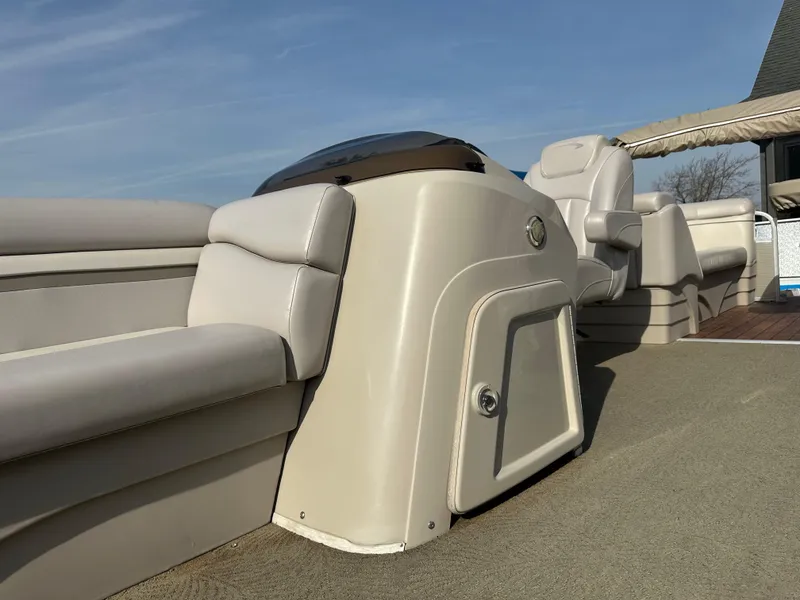 Slide: The Image of 2015 Bennington S24 boat interior with beige seating and helm under clear blue sky. - 17